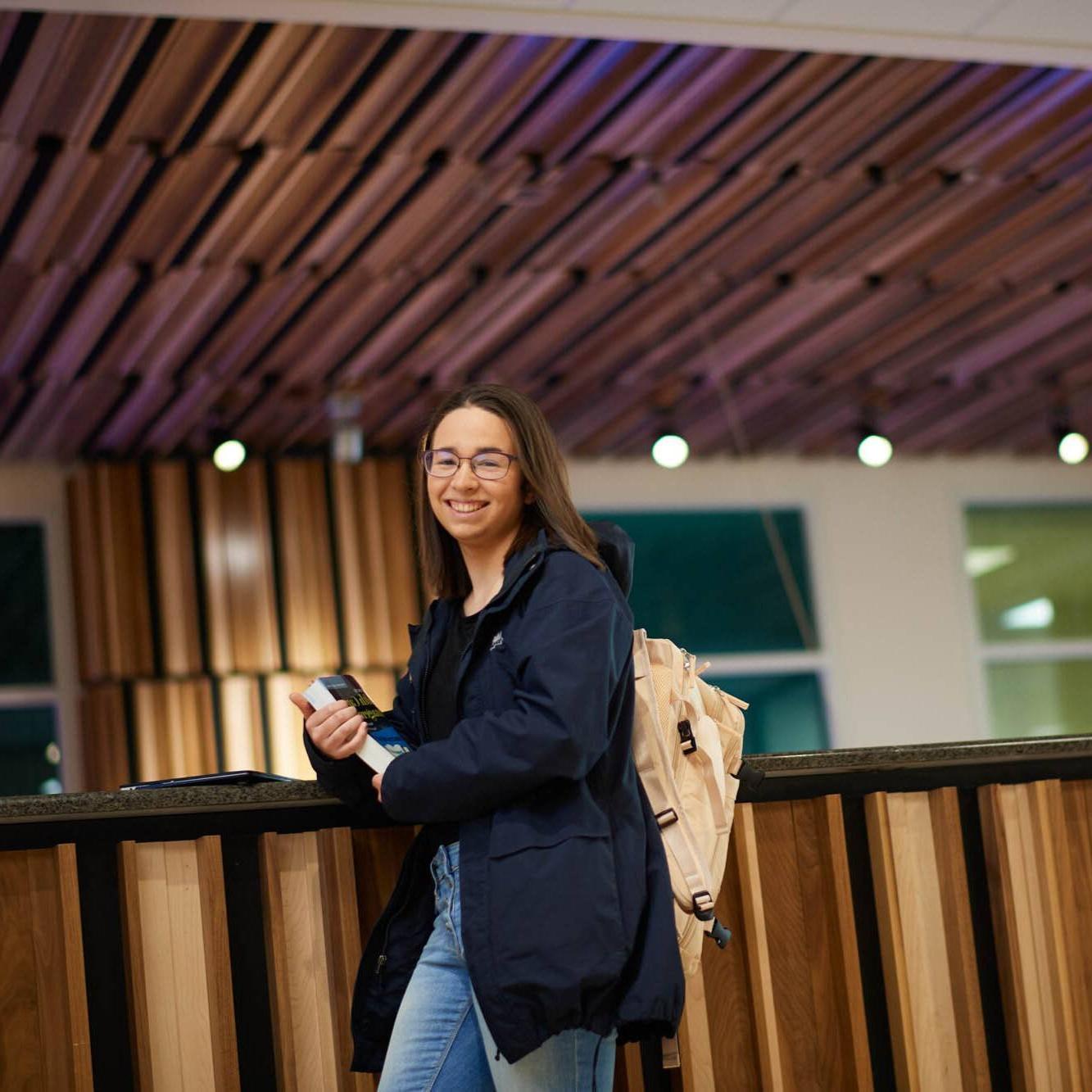 An adult learner smiles holding a book